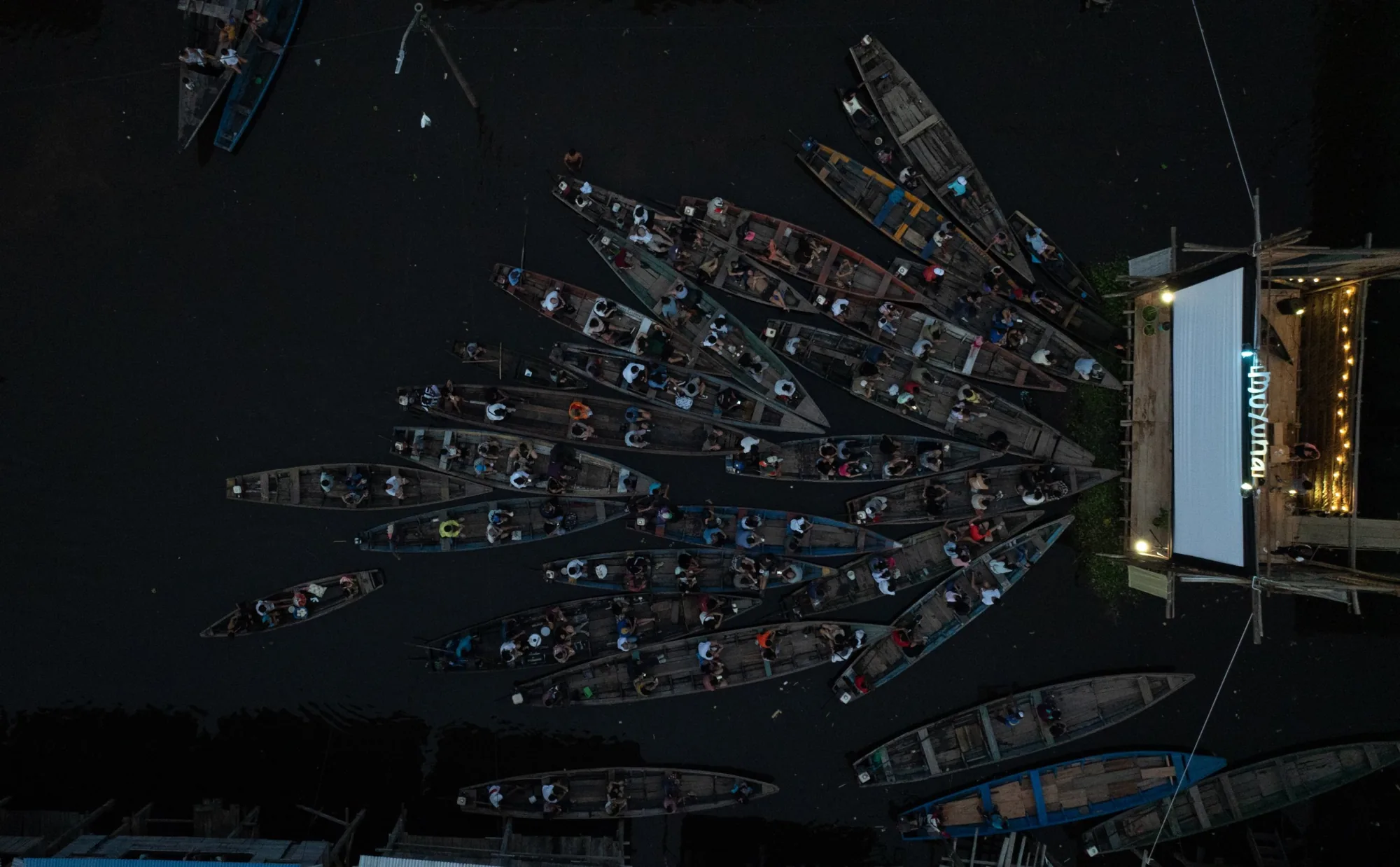 Canoas llenas de público frente a la pantalla de Muyuna, vistas desde arriba